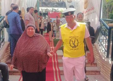 رجال الأمن يساعدون كبار السن للوصول إلى لجان انتخابات مجلس الشيوخ في المنوفية